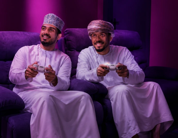 Two Omani men playing video games in traditional dress at Playcation.