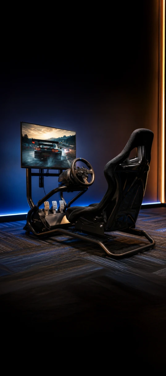 Realistic driving simulator setup with racing seat, steering wheel, and large screen at Playcation.
